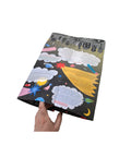 Photo showing a hand holding the folded Mapology Guide “What’s With This Gratitude Thing?” revealing its colourful interior filled with stars, planets, and gratitude prompts.