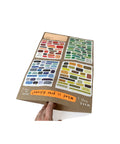 Hand holding open Mapology Guide showing colourful illustrated decision dilemmas