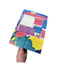 Photo showing a hand holding open the folded Mapology Guide “The Expedition Towards a Meaningful Life,” revealing colourful illustrated sections and text exploring purpose, perseverance, and new life directions.
