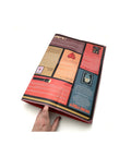 Photo showing a hand holding open the folded Mapology Guide “Who Are You?”, revealing sections of illustrated prompts and reflections about identity, purpose, and personal growth.